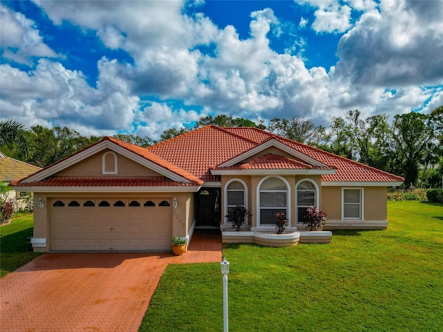 mediterranean / spanish-style home featuring a front lawn, a tiled roof, stucco siding, a garage, and driveway