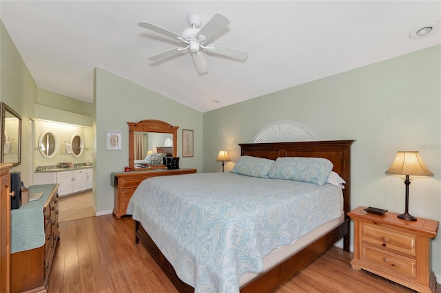 bedroom featuring light wood-type flooring, ceiling fan, ensuite bathroom, and vaulted ceiling