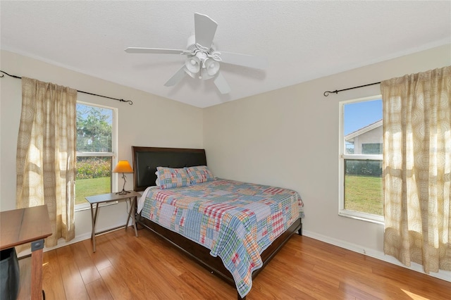 bedroom with a textured ceiling, baseboards, ceiling fan, and wood finished floors