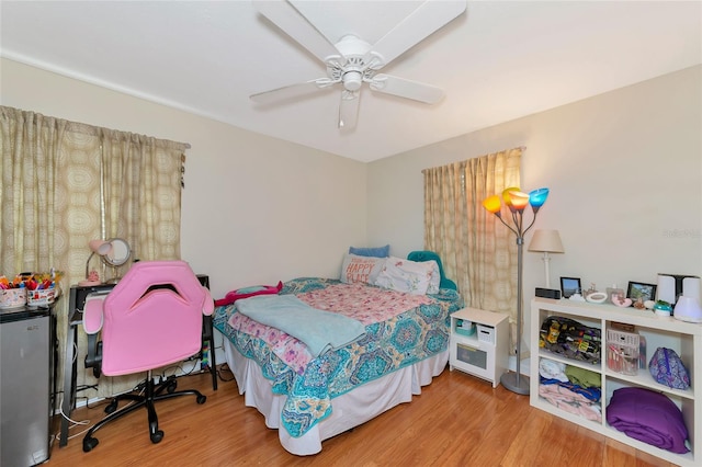 bedroom featuring fridge, wood finished floors, and ceiling fan