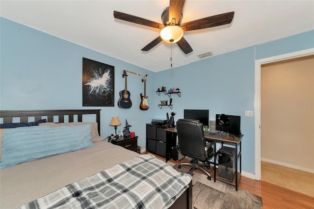 bedroom with wood finished floors, visible vents, baseboards, and ceiling fan