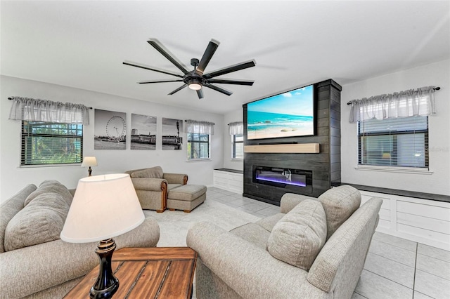 tiled living room featuring a large fireplace and ceiling fan