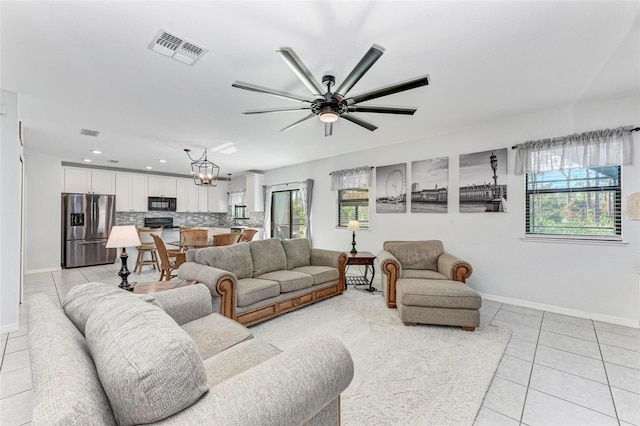 living room with ceiling fan with notable chandelier and light tile patterned floors