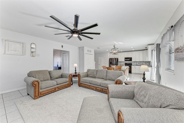 tiled living room with ceiling fan with notable chandelier