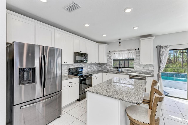 kitchen featuring sink, black appliances, light stone counters, a kitchen breakfast bar, and a center island