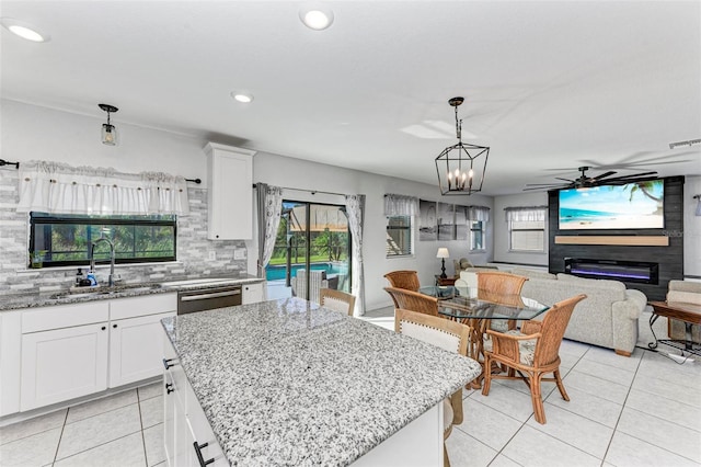 kitchen featuring a kitchen island, decorative light fixtures, sink, white cabinets, and ceiling fan with notable chandelier