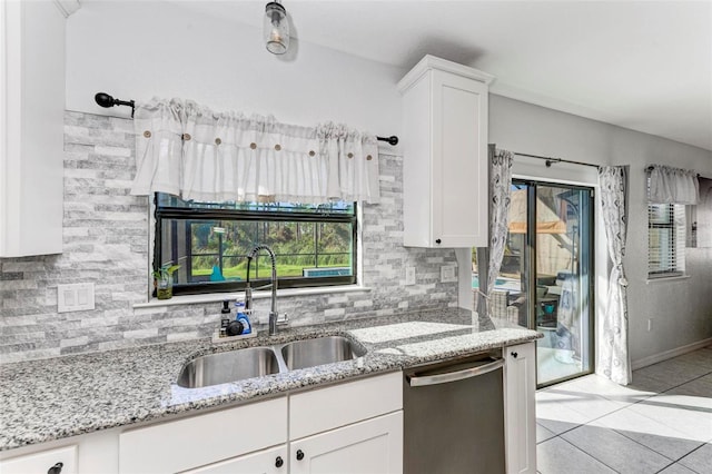 kitchen with tasteful backsplash, stainless steel dishwasher, sink, and white cabinets