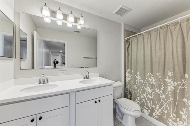 bathroom with tile patterned flooring, vanity, a textured ceiling, and toilet