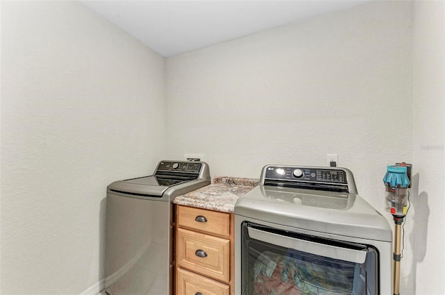 clothes washing area with cabinets and washer and clothes dryer