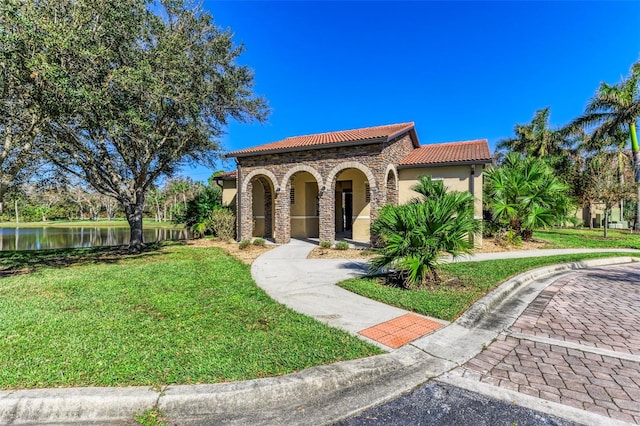 mediterranean / spanish-style home with a front yard and a water view