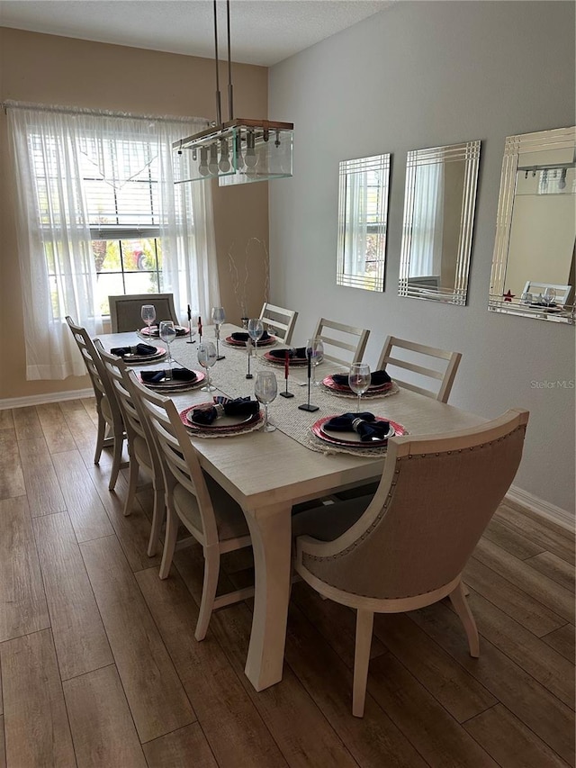 dining space with hardwood / wood-style flooring and a notable chandelier