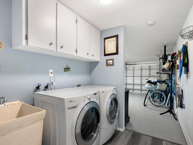 laundry room with cabinets, sink, a textured ceiling, washing machine and clothes dryer, and dark wood-type flooring