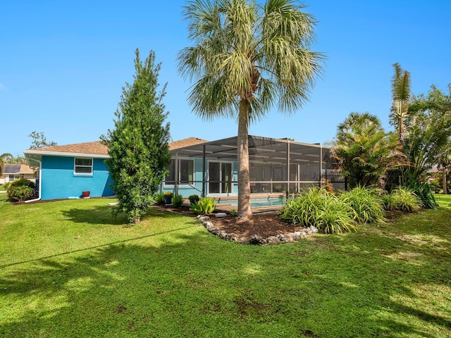 rear view of property with a lawn and a lanai