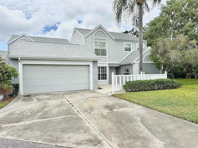 view of property featuring a garage and a front lawn