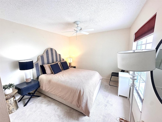 bedroom with light carpet, ceiling fan, baseboards, and a textured ceiling