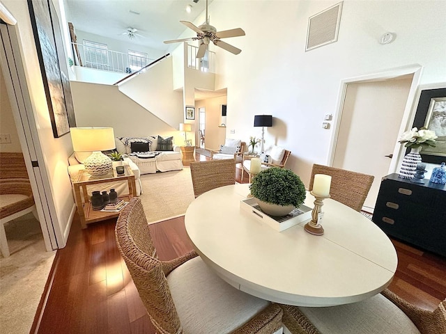 dining room featuring a towering ceiling, ceiling fan, wood finished floors, and visible vents