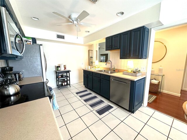 kitchen with stainless steel appliances, a sink, visible vents, light countertops, and backsplash