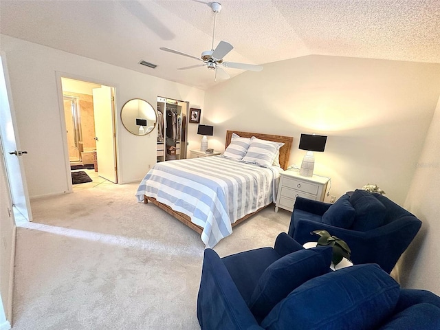 bedroom featuring light carpet, visible vents, lofted ceiling, ensuite bath, and a textured ceiling