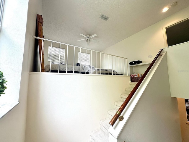 staircase featuring a textured ceiling, recessed lighting, visible vents, and a ceiling fan