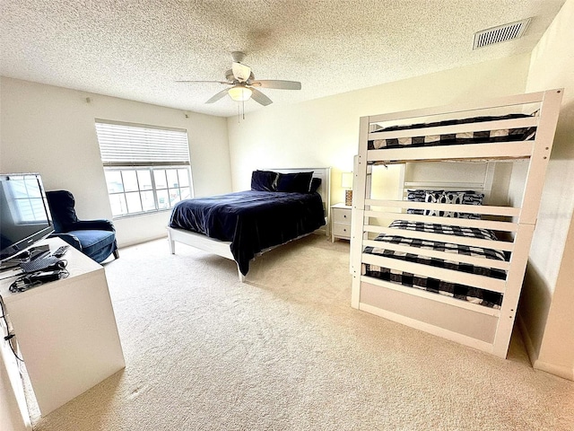 bedroom with a textured ceiling, a ceiling fan, visible vents, and light colored carpet