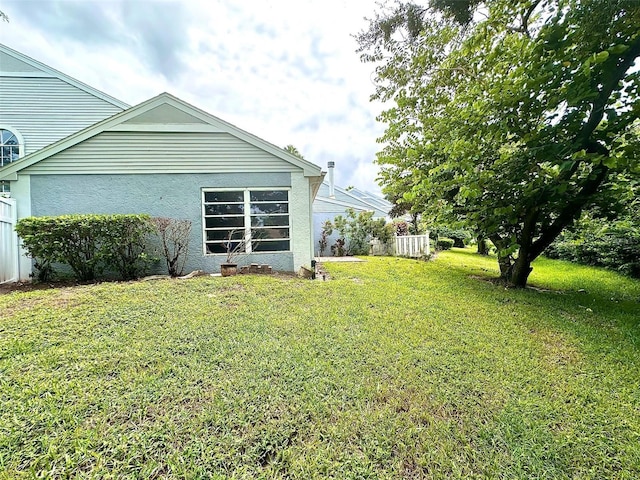 exterior space with stucco siding, fence, and a yard