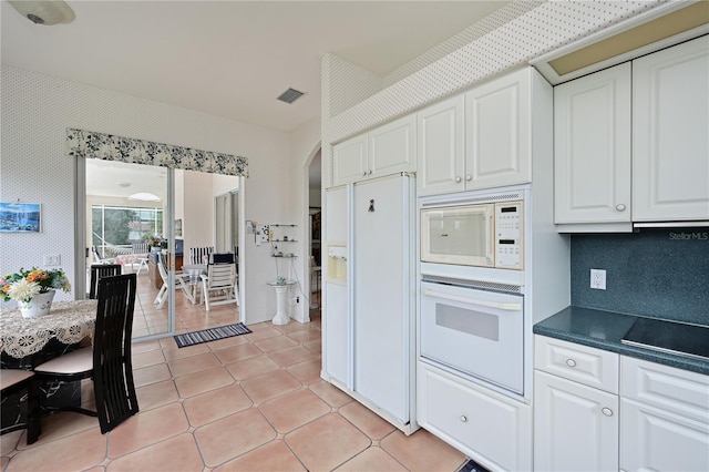 kitchen featuring white cabinets, light tile patterned flooring, white appliances, and backsplash