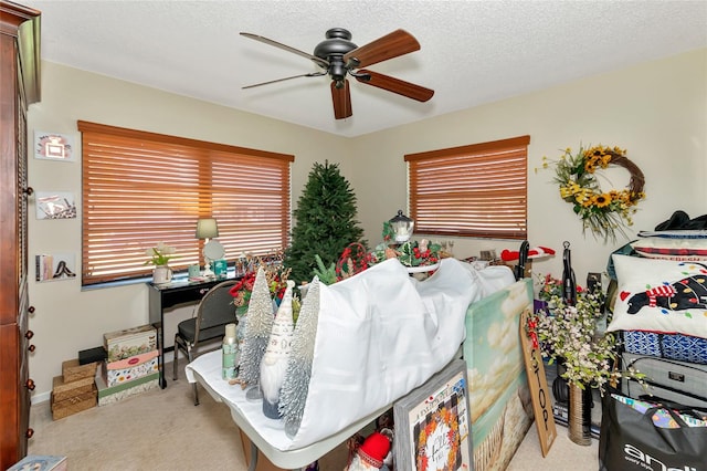 bedroom featuring ceiling fan, light colored carpet, and a textured ceiling