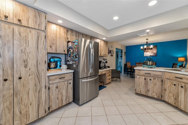 kitchen featuring sink, pendant lighting, a notable chandelier, stainless steel refrigerator, and light tile patterned flooring