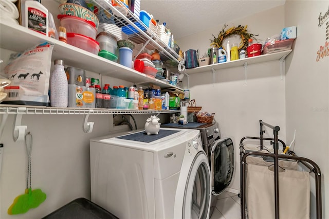 laundry area with independent washer and dryer, a textured ceiling, and tile patterned floors