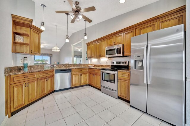 kitchen featuring sink, light stone counters, appliances with stainless steel finishes, pendant lighting, and vaulted ceiling