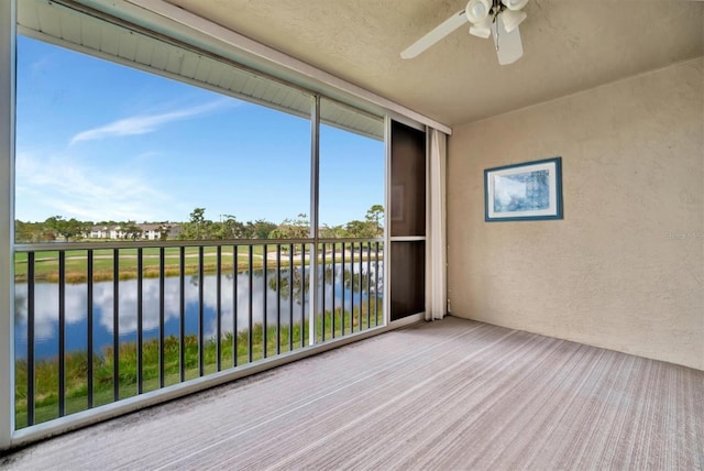 unfurnished sunroom with ceiling fan and a water view