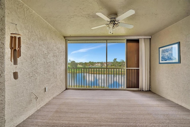 unfurnished sunroom featuring a water view and ceiling fan