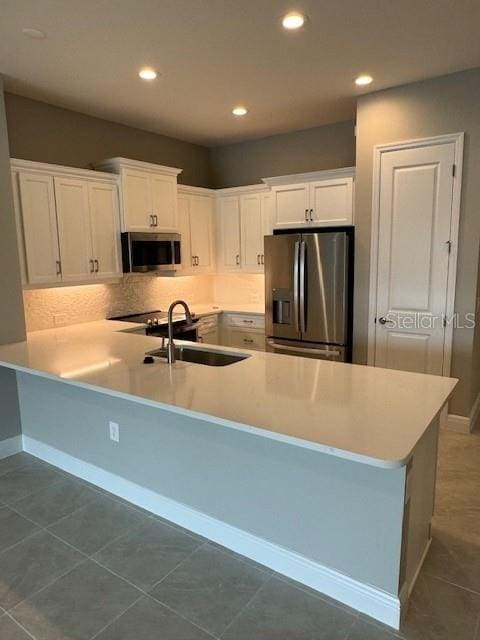 kitchen with stainless steel appliances, tile patterned flooring, white cabinetry, and sink