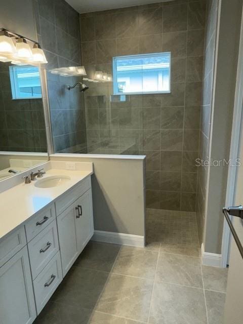 bathroom featuring tile patterned flooring, vanity, and a tile shower