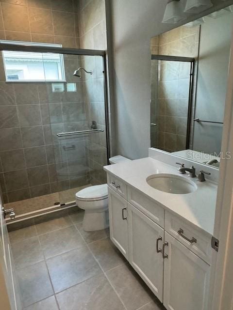 bathroom featuring toilet, an enclosed shower, vanity, and tile patterned floors