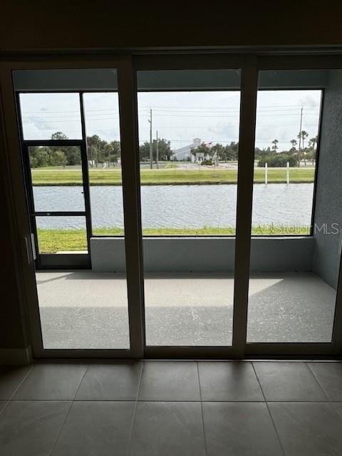 doorway with a water view, tile patterned flooring, and a healthy amount of sunlight