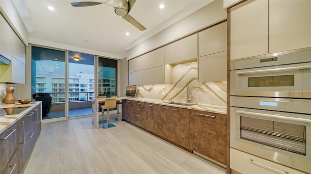 kitchen featuring light hardwood / wood-style floors, sink, light stone countertops, stainless steel double oven, and crown molding