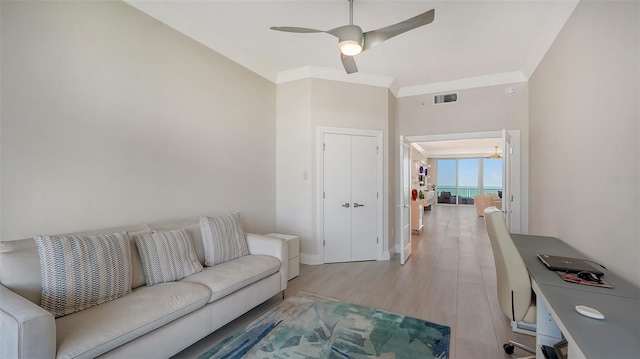 living room with light wood-type flooring, ceiling fan, and crown molding