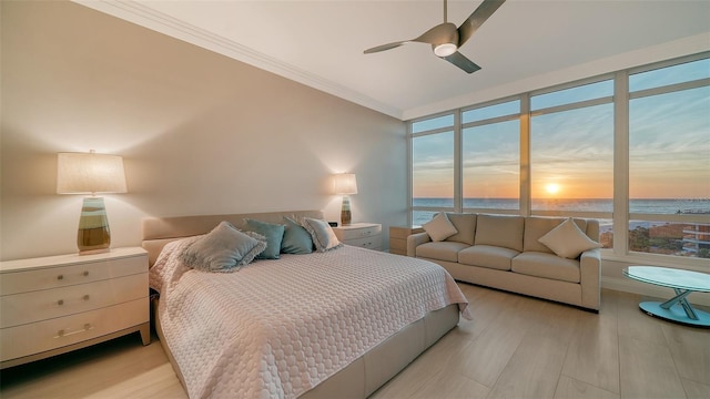 bedroom featuring multiple windows, light hardwood / wood-style floors, a water view, and ceiling fan