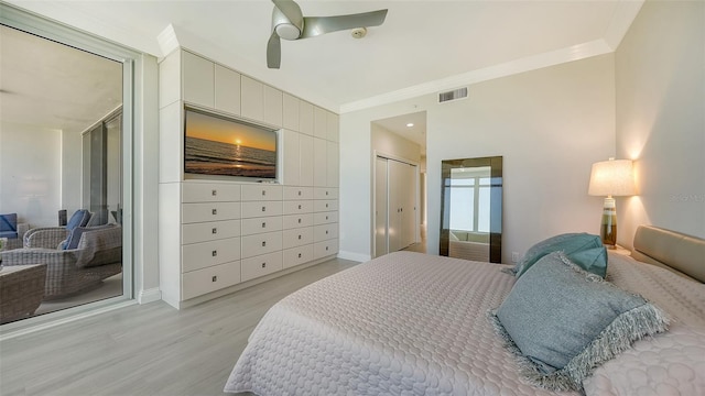 bedroom with light hardwood / wood-style floors, ceiling fan, crown molding, and a closet