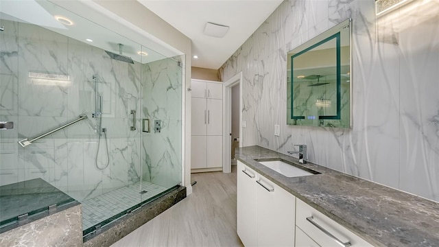 bathroom with vanity, an enclosed shower, and tile walls