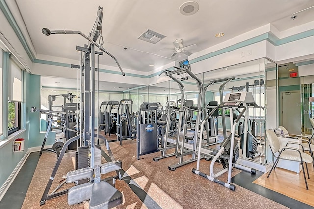 workout area featuring ceiling fan and a tray ceiling