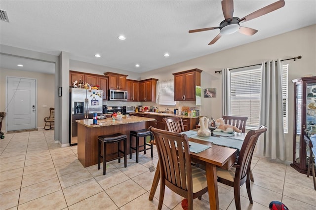 tiled dining room with a textured ceiling and ceiling fan