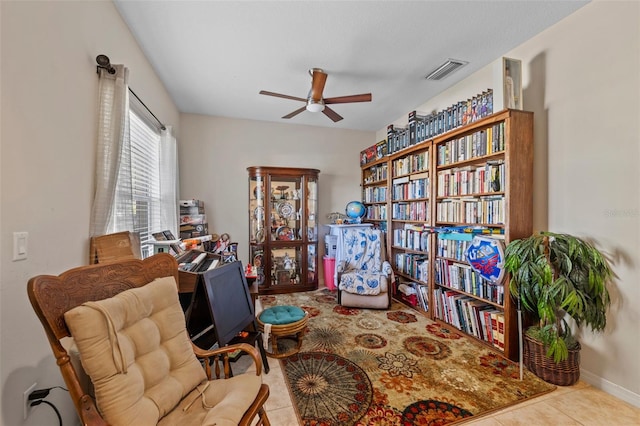 living area with light tile patterned floors and ceiling fan