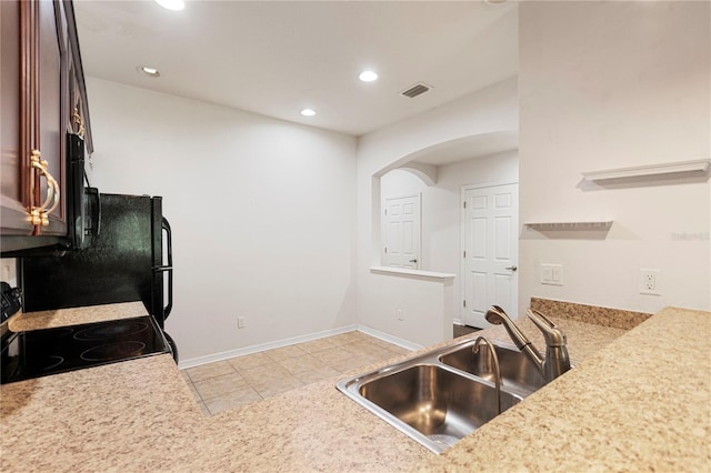 kitchen featuring black appliances, light tile patterned floors, and sink