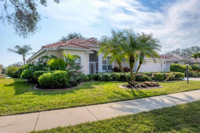 mediterranean / spanish home featuring a tile roof, an attached garage, a front yard, and stucco siding