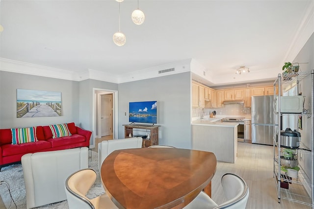 dining area featuring light hardwood / wood-style floors, sink, and crown molding