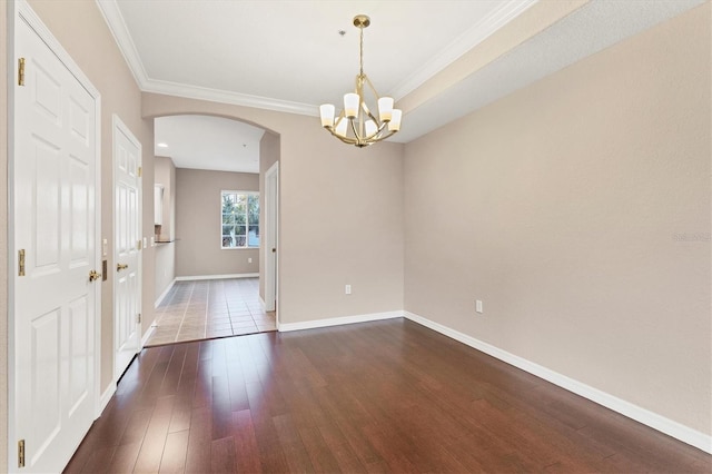 spare room featuring a notable chandelier, crown molding, and dark hardwood / wood-style floors