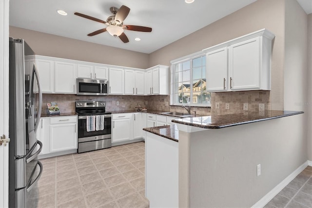 kitchen with white cabinetry, backsplash, kitchen peninsula, dark stone countertops, and appliances with stainless steel finishes