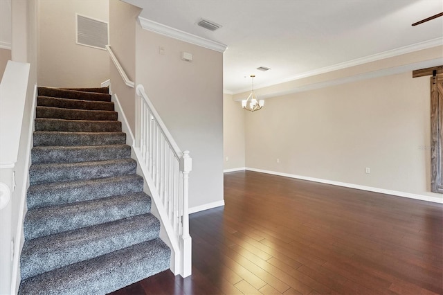 stairway with crown molding, hardwood / wood-style floors, and a chandelier